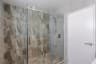 Sliding glass shower enclosure with chrome hardware against grey marble-look tile.