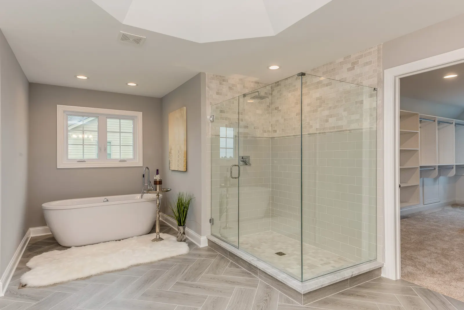 Frameless corner glass shower enclosure with a hinged door beside a freestanding tub.