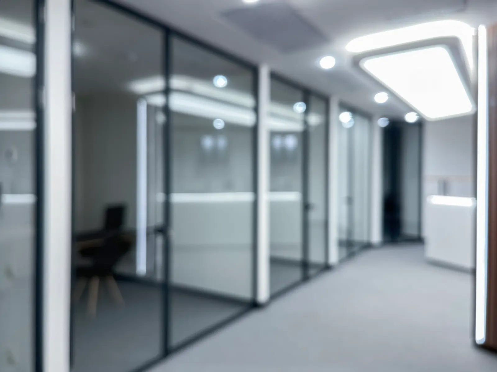 Blurred office corridor lined with black-framed glass partition walls.