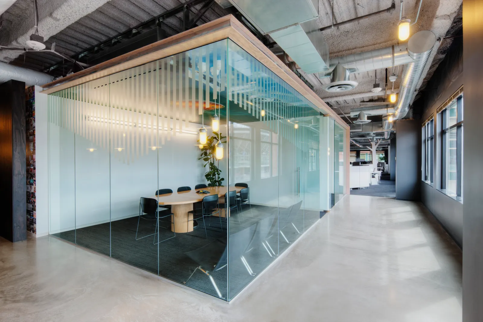 Glass-walled meeting room with frosted stripe film in an industrial office.