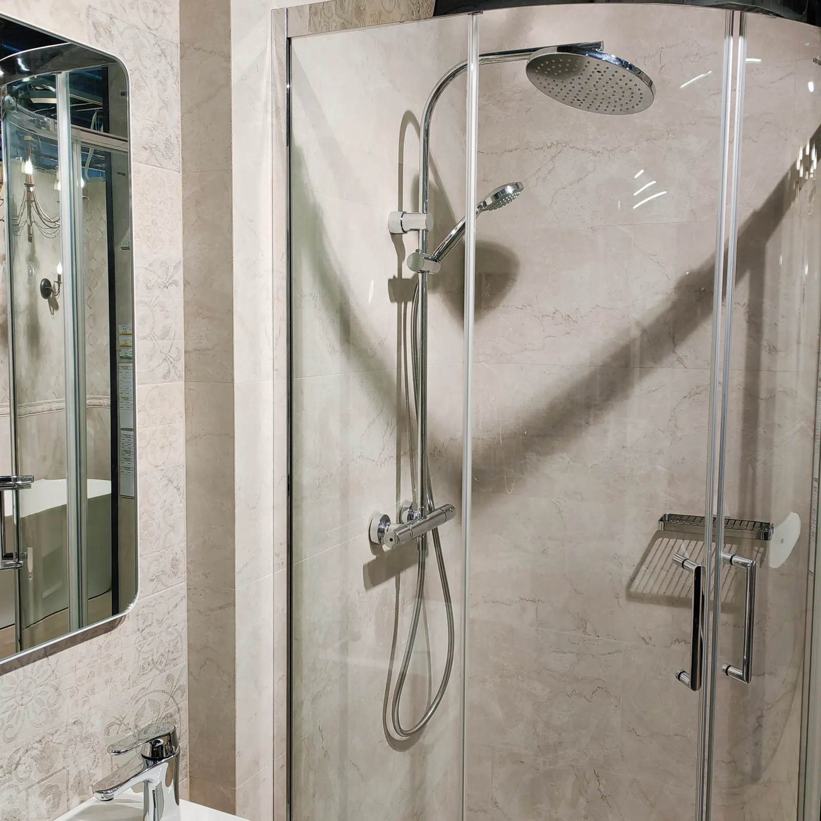 Curved corner glass shower enclosure with a chrome frame and sliding doors against beige marble tile.