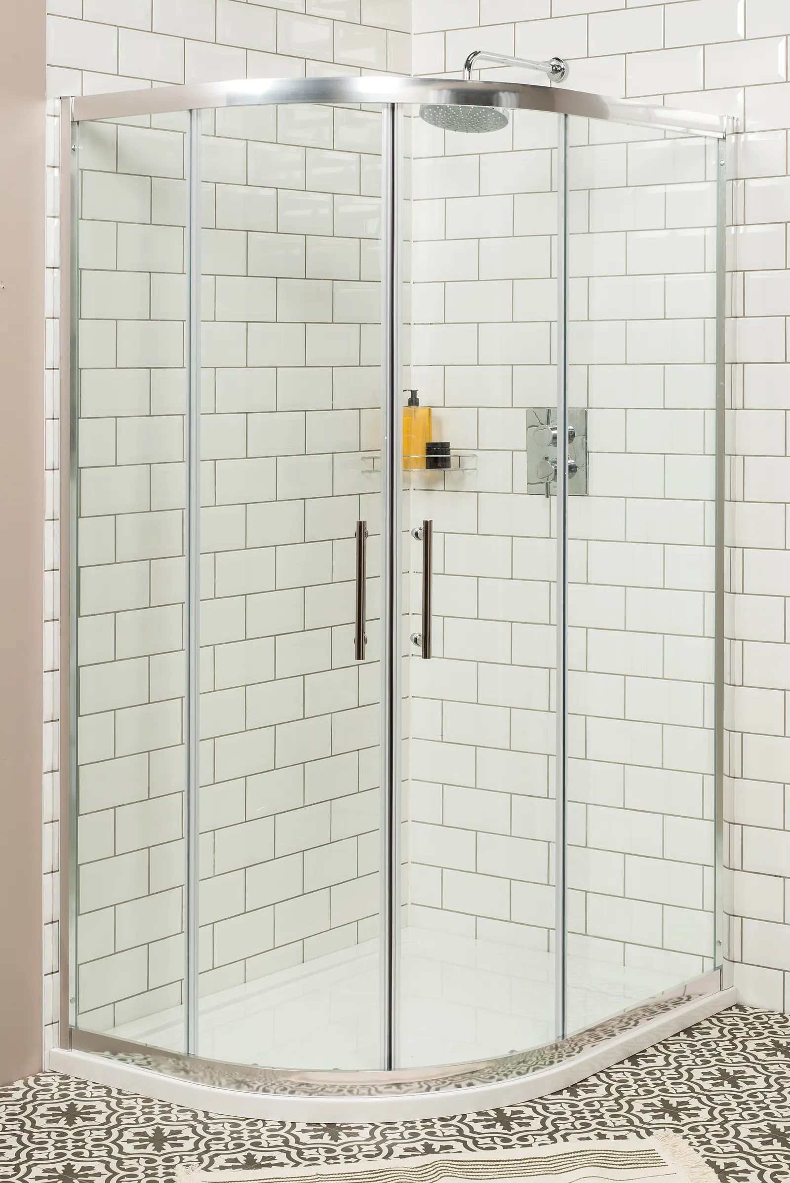 Quadrant corner shower enclosure with chrome-framed sliding doors and white subway tile.
