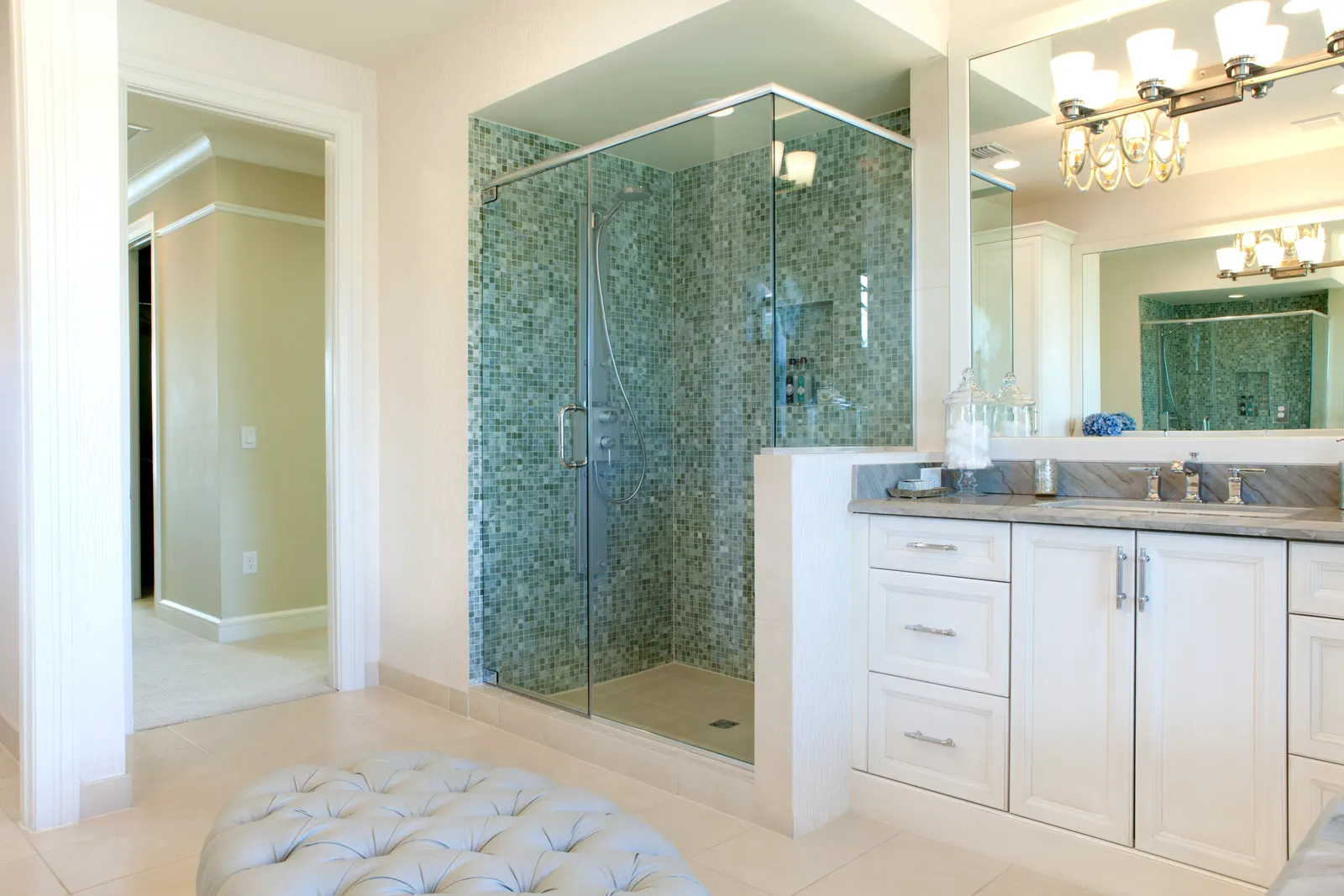 Frameless corner glass shower with green mosaic tile beside a double vanity.