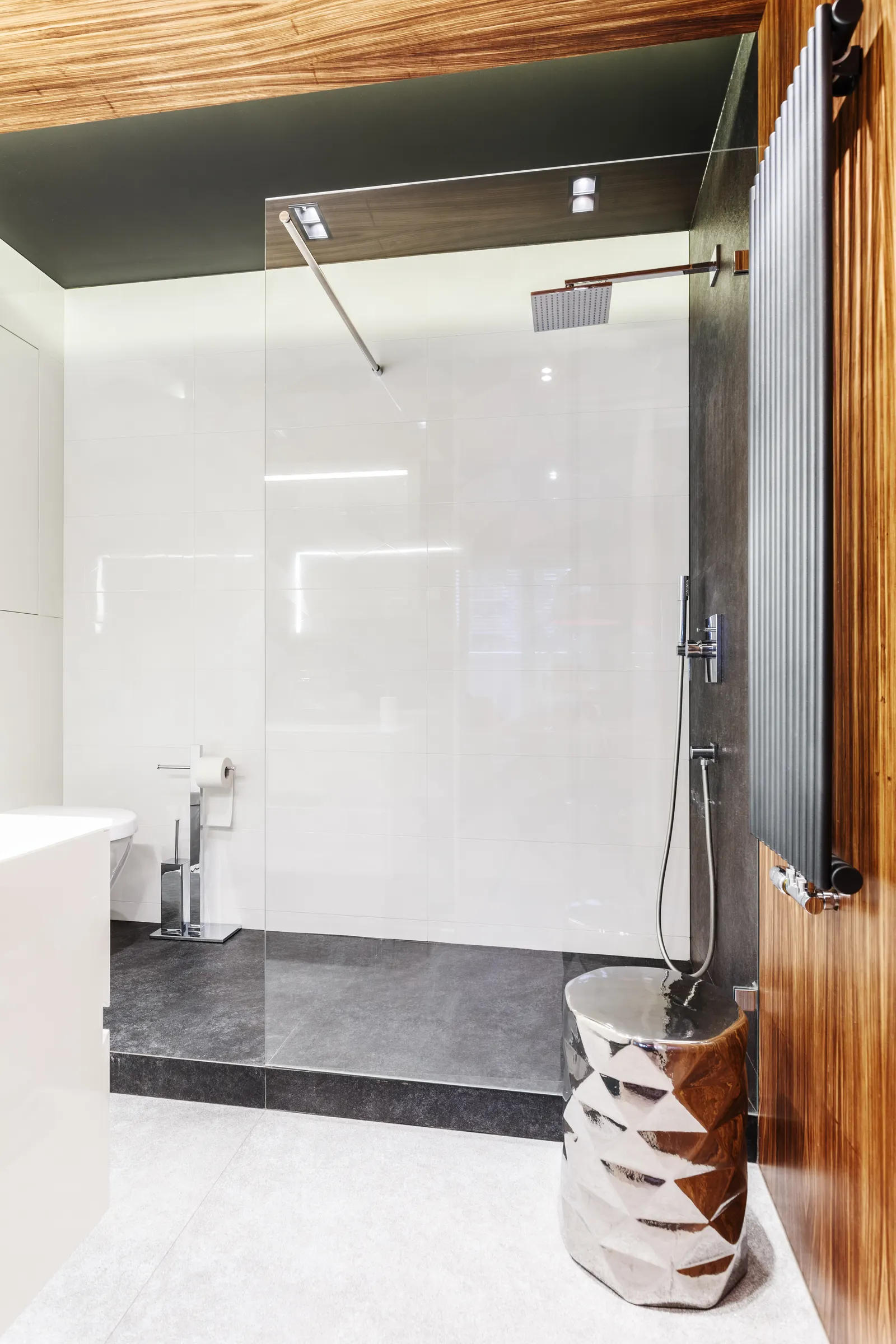 Curbless walk-in shower with a fixed glass panel, white gloss tile, and wood ceiling.
