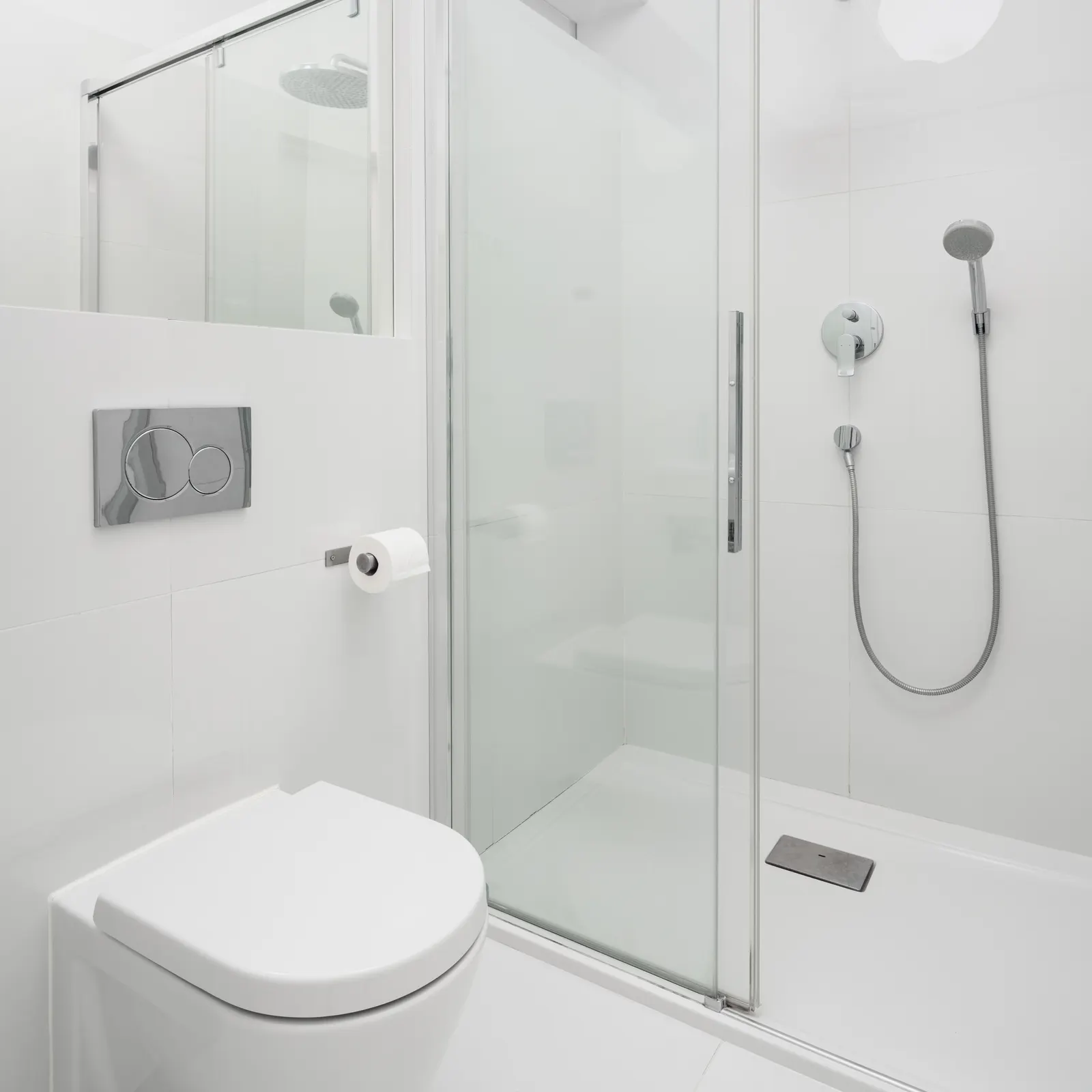 White bathroom with a framed sliding glass shower enclosure and handheld shower.