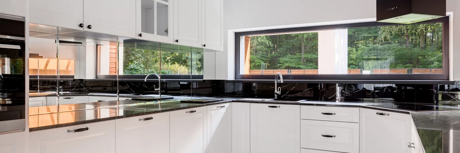 Black glossy glass and mirrored splashback in a white classic kitchen.