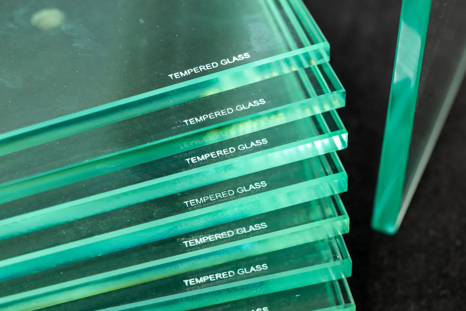 Stacked glass panels with edges labeled tempered glass showing a green tint.