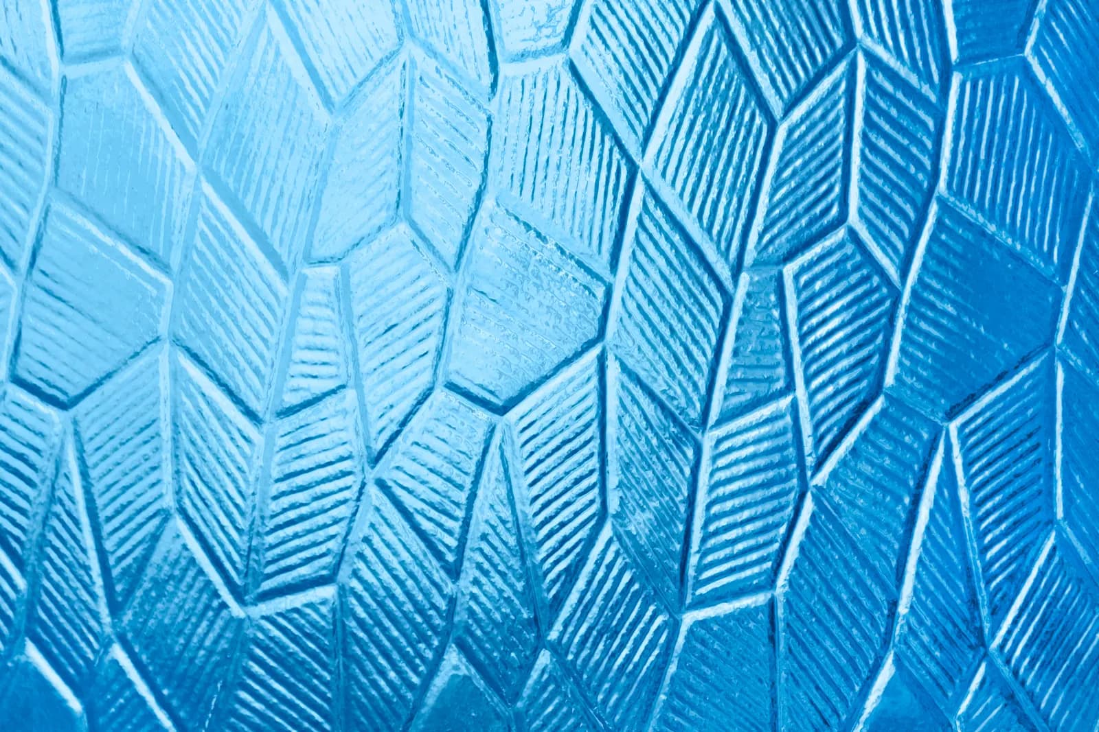 Close-up of geometric diamond-patterned obscure glass in blue tones.