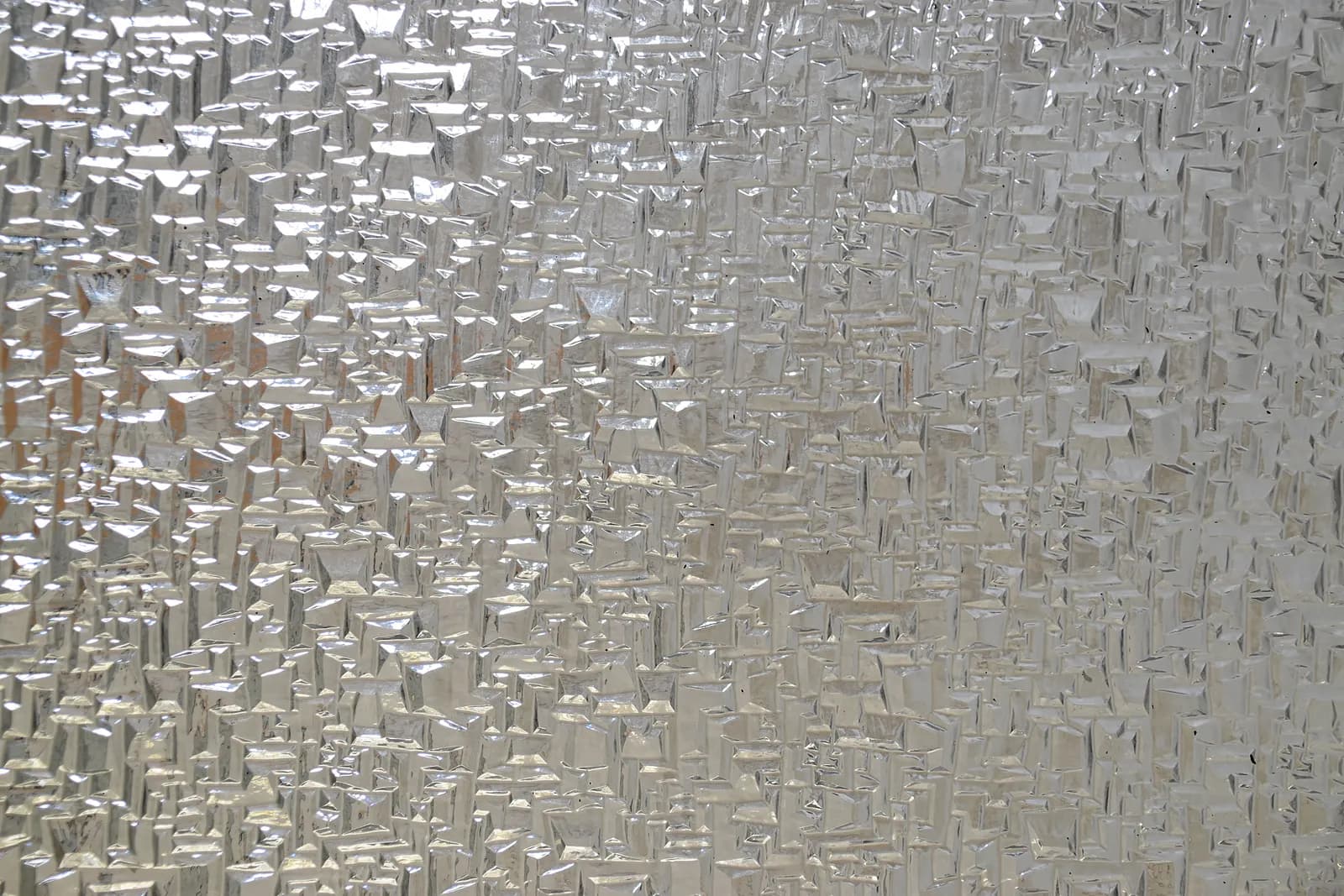 Close-up of a silvery textured cathedral glass surface catching light.