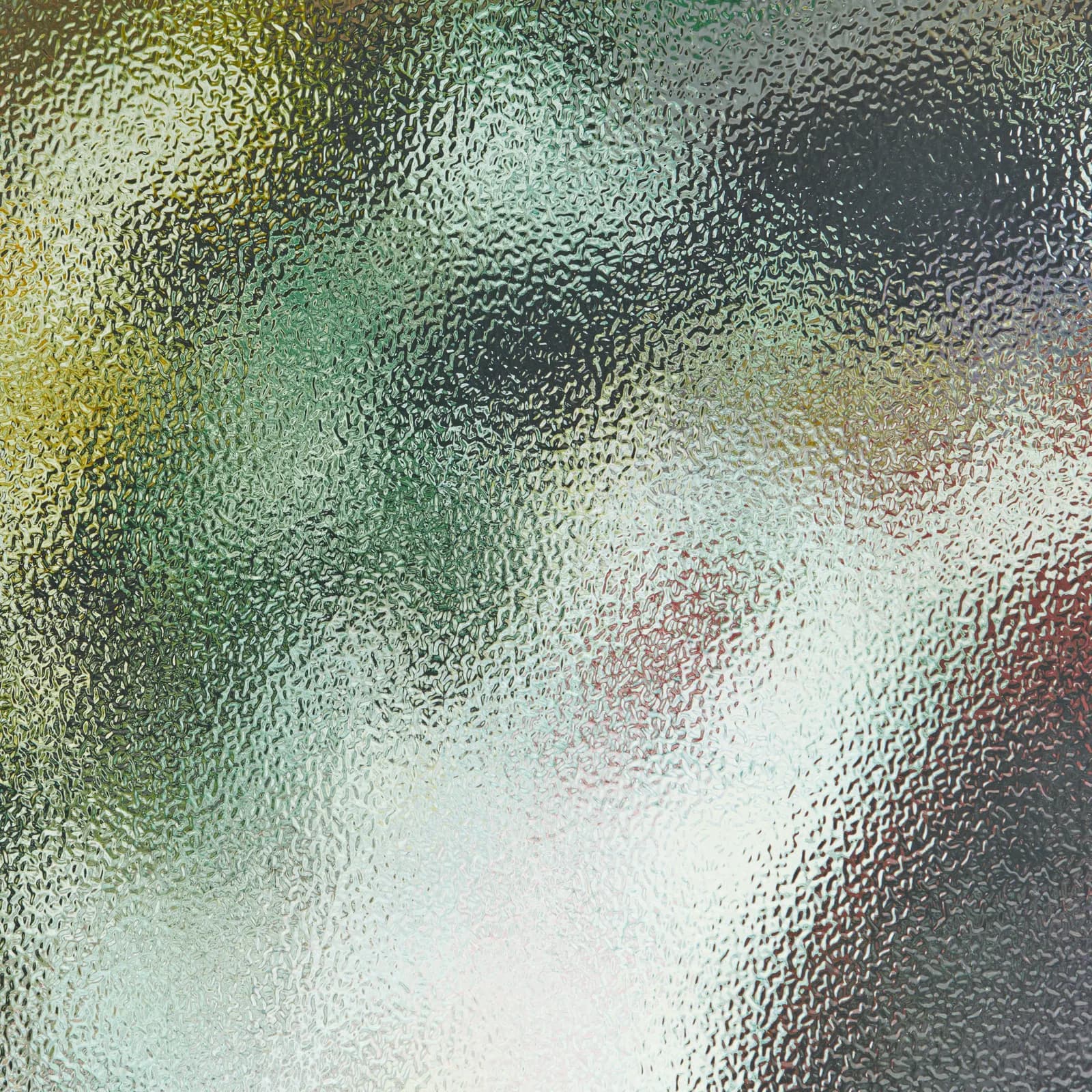 Close-up of frosted hammered-texture glass blurring the colors behind it.