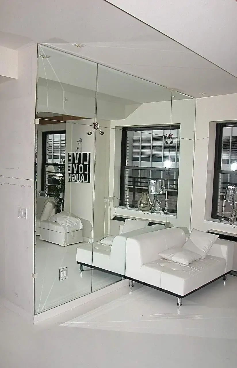 Floor-to-ceiling mirrored feature wall in a furnished room.