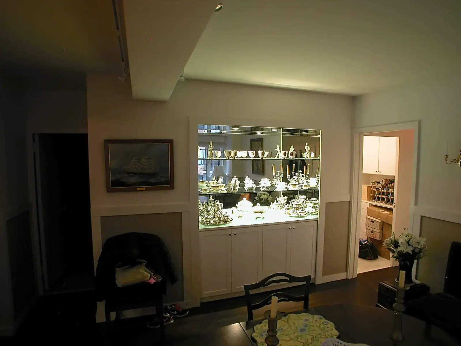 Mirrored display cabinet with glass shelves and interior lighting.