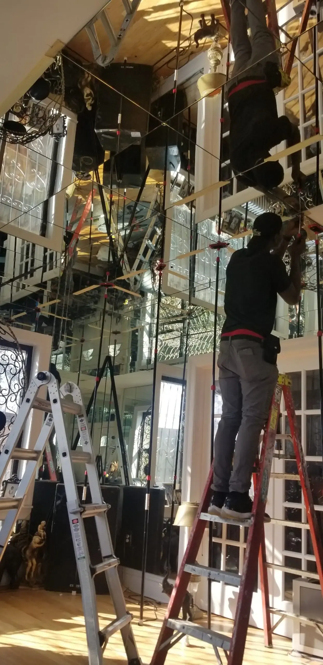 Commercial mirrored wall installation with ladders and work crew.